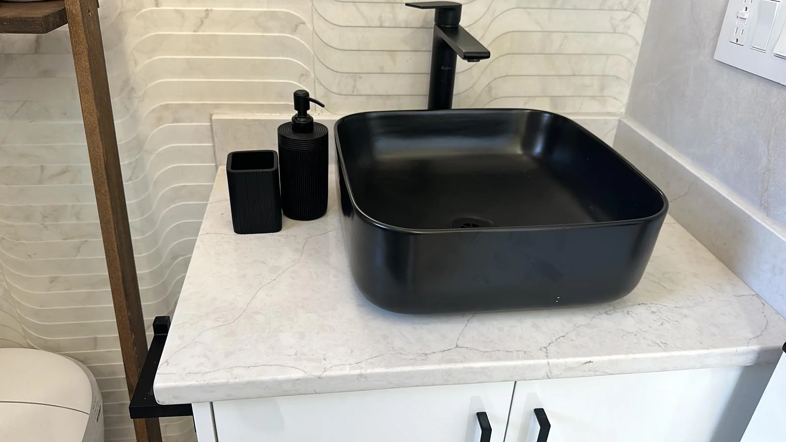Bathroom vanity with vessel sink on a light stone surface.
