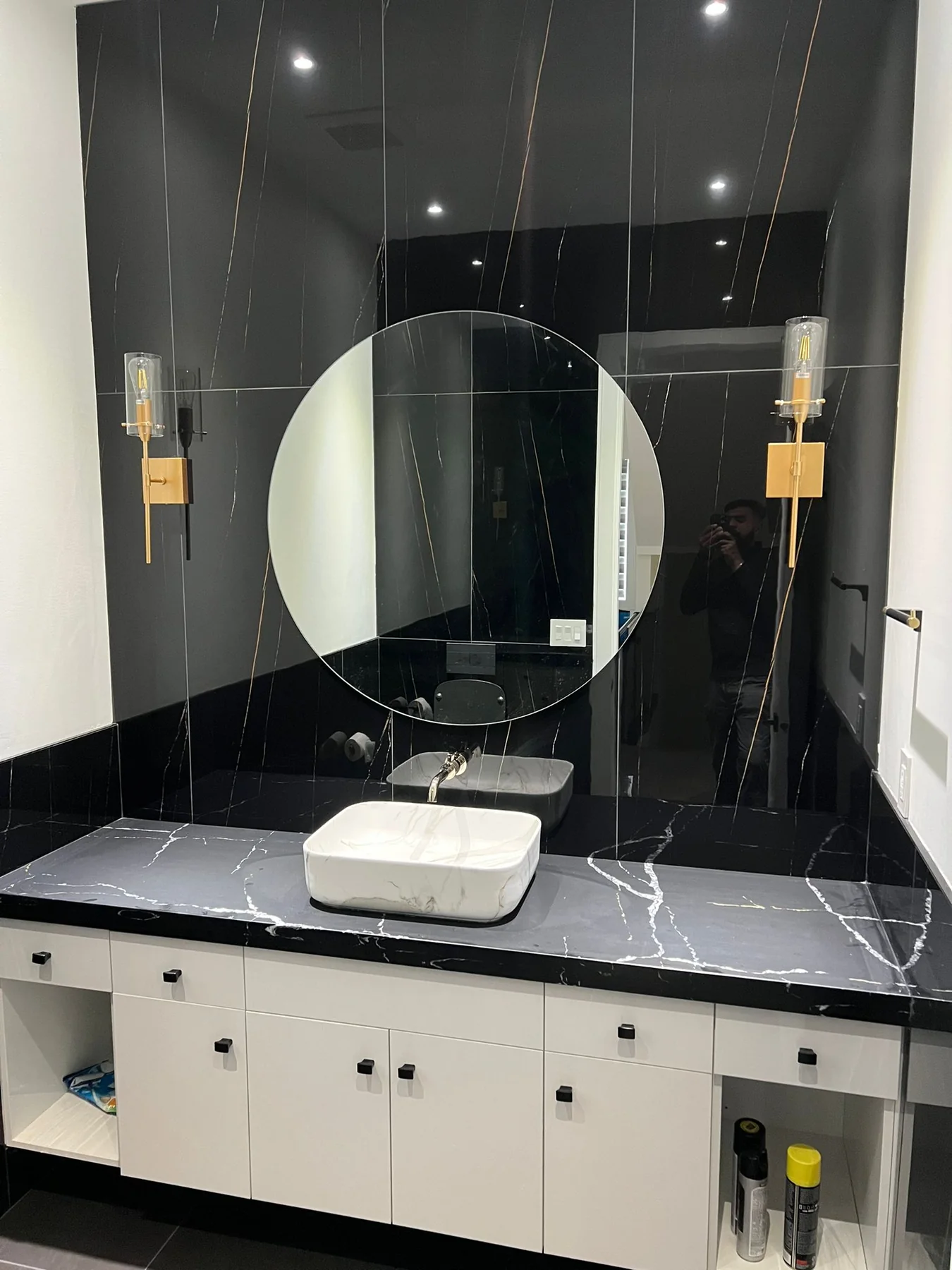 Bathroom vanity with black stone wall and custom countertop surface.