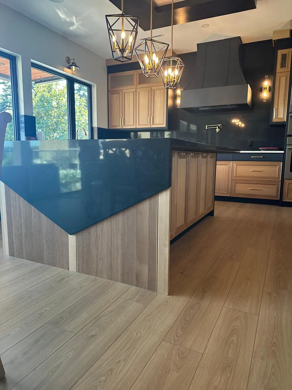 Kitchen with blue base cabinets and stone countertop.