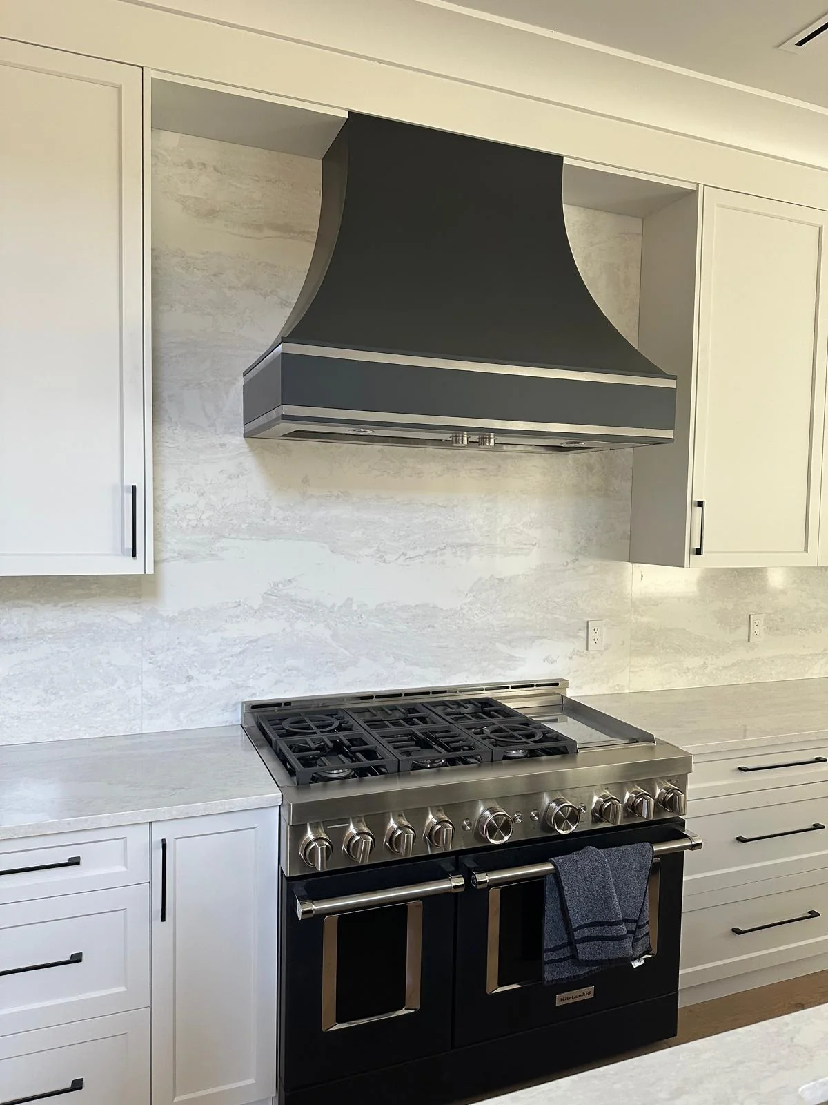 Kitchen range wall with stone backsplash and countertop.